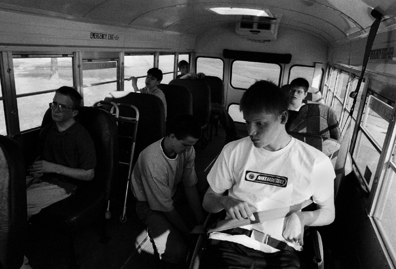 Jason Craig, right, gets strapped into place on a bus for special needs students before the start of school. Prior to his accident, the popular football player used to make fun of special needs students. "Now I know what they go through," he said.